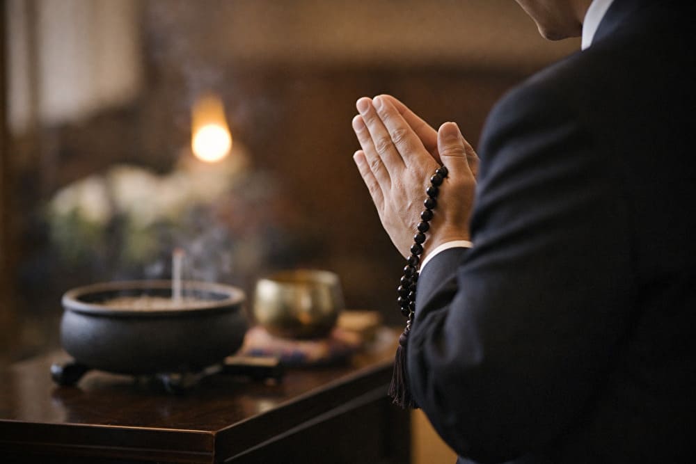 葬儀で静かに合掌する手元。数珠を持ち、落ち着いた所作を意識している様子